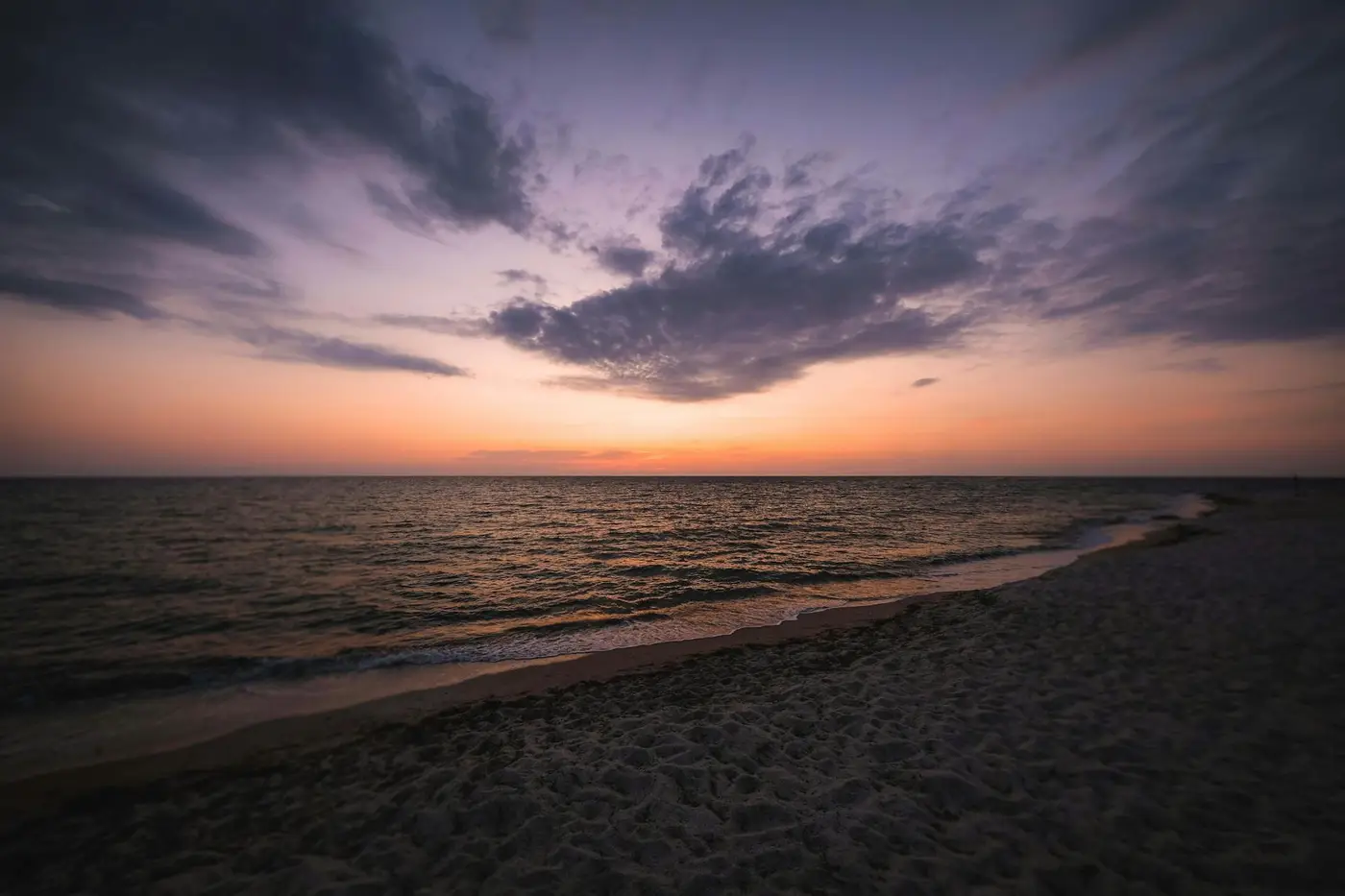 Tranquil Mediterranean beach at sunset with soft purple sky and gentle waves