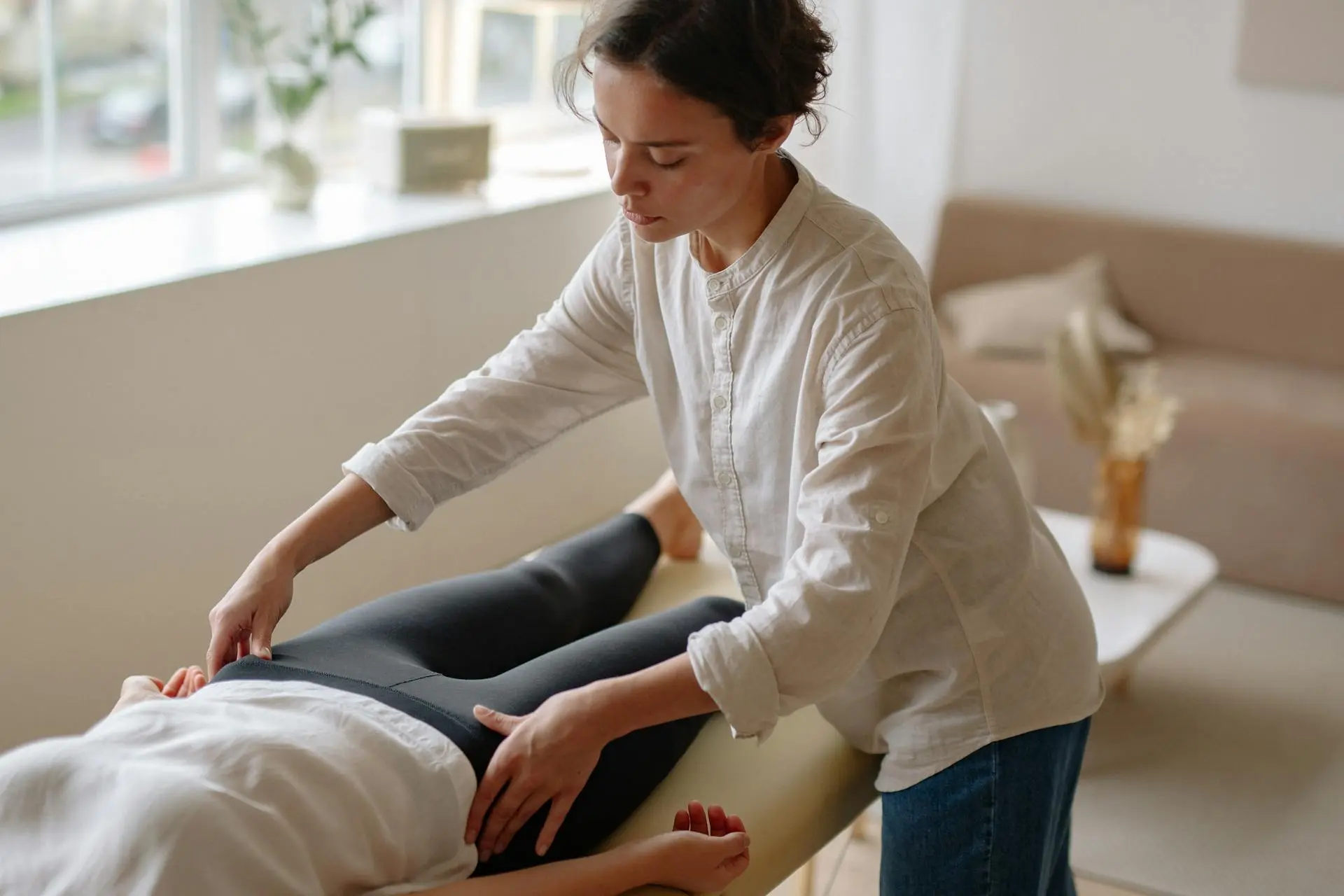 Physiotherapist treating a patient on a treatment table in a bright, modern clinic